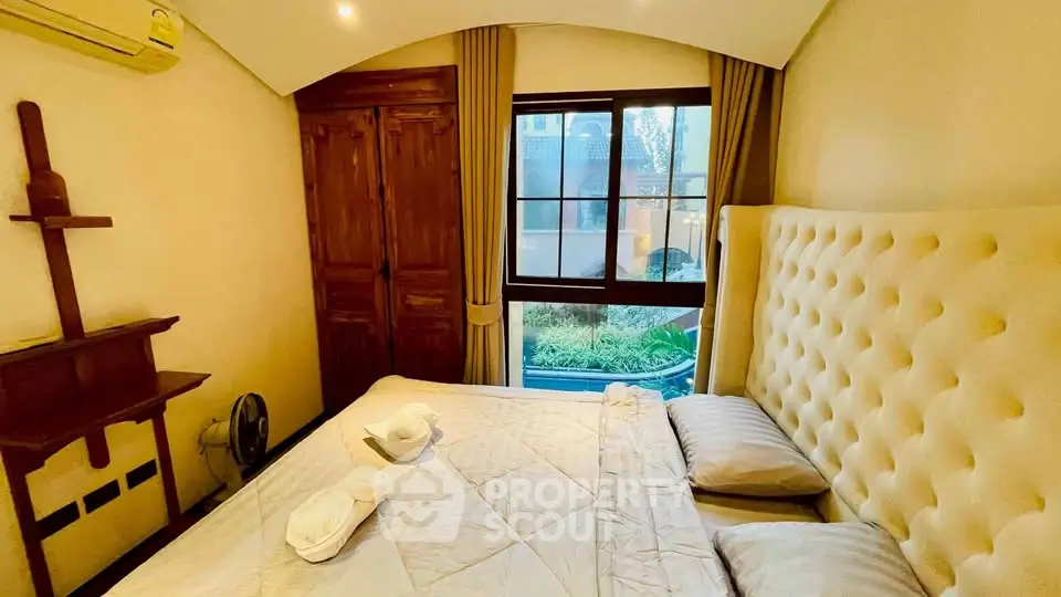 Cozy bedroom with plush headboard and garden view, perfect for relaxation.