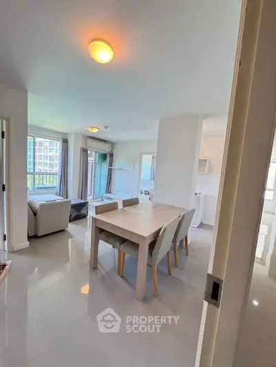 Spacious modern living room with dining area and large windows in a bright apartment.