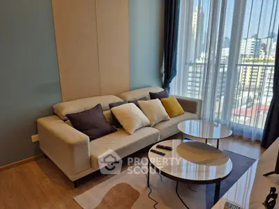 Modern living room with city view, stylish sofa, and elegant coffee tables in a high-rise apartment.