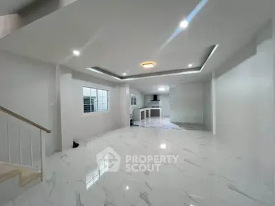 Spacious modern living room with open kitchen layout and elegant marble flooring.