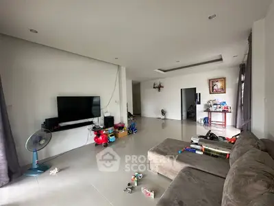 Spacious living room with modern decor and large TV, ideal for family gatherings.