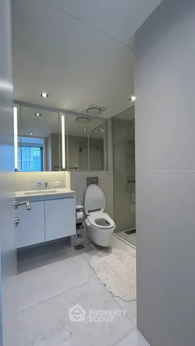 Modern bathroom with sleek fixtures and minimalist design, featuring a spacious shower and elegant lighting.