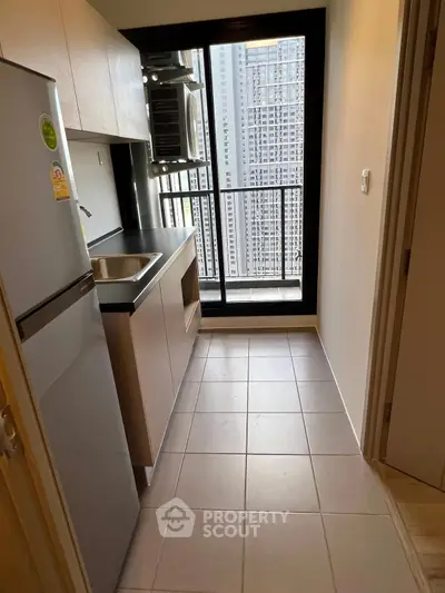 Modern compact kitchen with city view, featuring sleek cabinetry and stainless steel appliances.