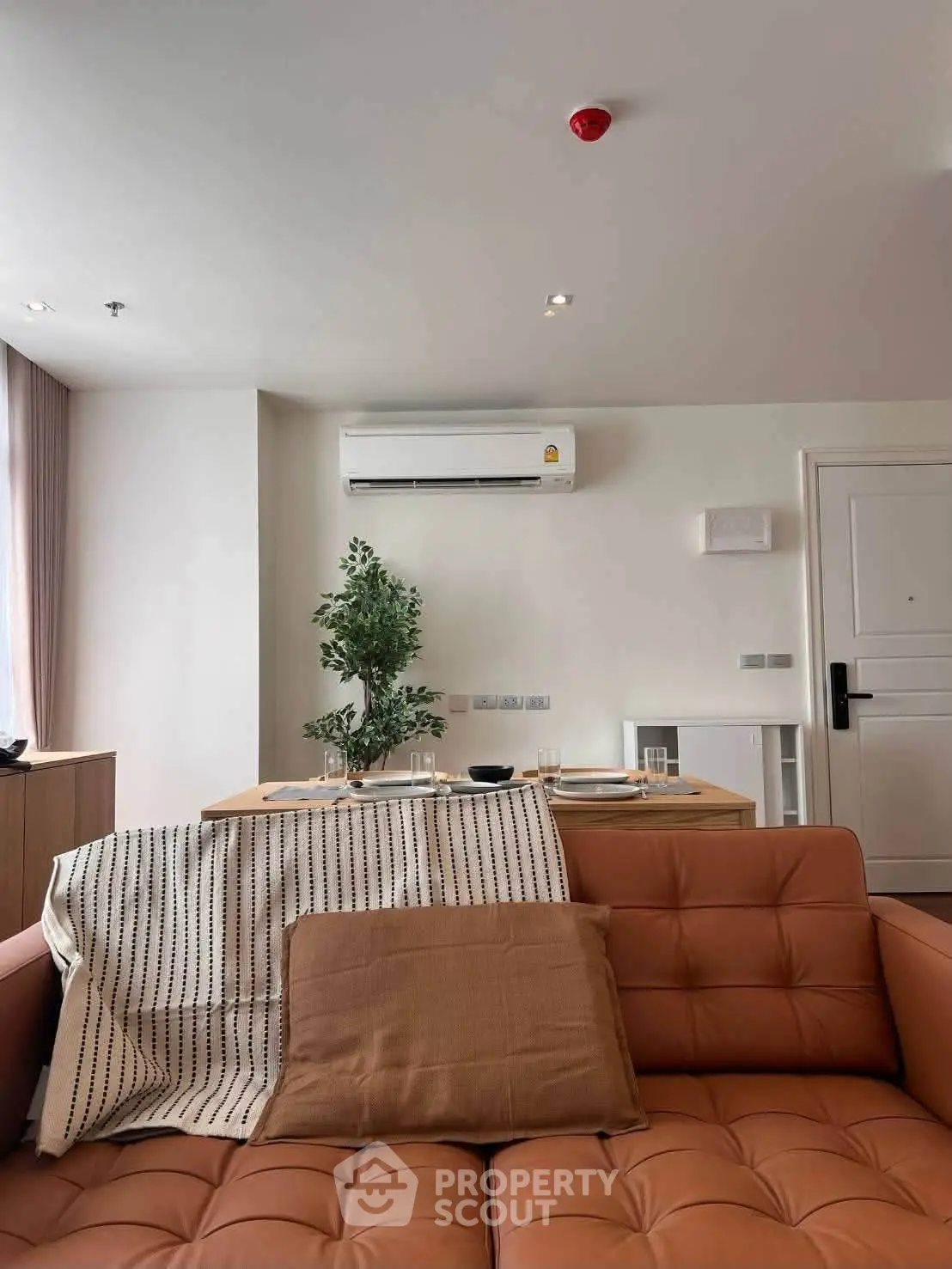 Modern living room with stylish sofa and dining area, featuring air conditioning and cozy decor.