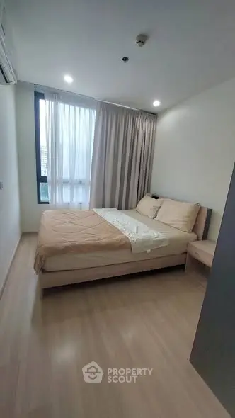Cozy bedroom with large window and modern furnishings in a stylish apartment.