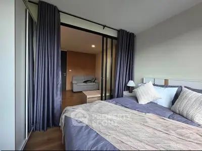 Modern bedroom with sliding glass doors leading to a cozy living area, featuring elegant decor and ample natural light.