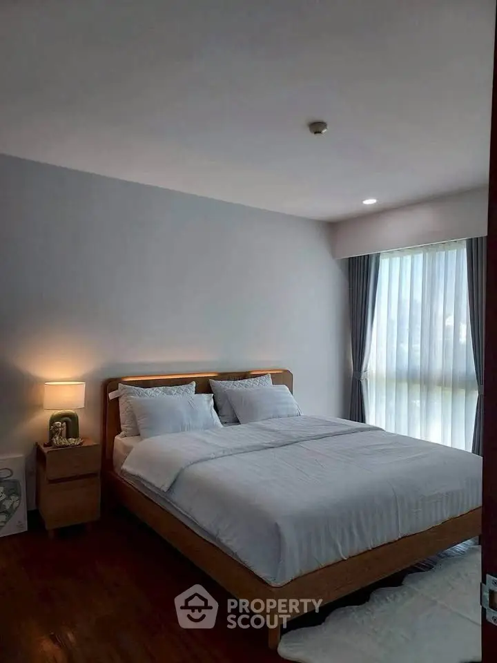 Cozy bedroom with modern decor and large window offering natural light.
