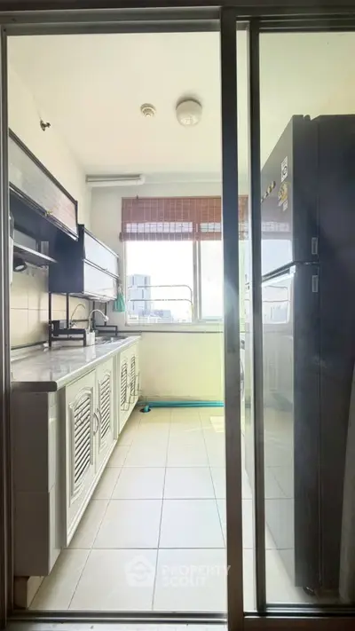 Bright kitchen with large window and modern appliances in a high-rise apartment.