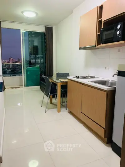 Modern kitchen with open layout and city view from balcony in high-rise apartment.
