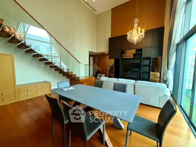 Luxurious modern living room with high ceilings, elegant chandelier, and stylish staircase in a contemporary apartment.