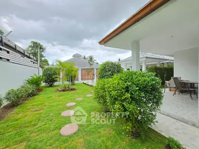 Charming garden view of modern home with lush greenery and cozy patio area.