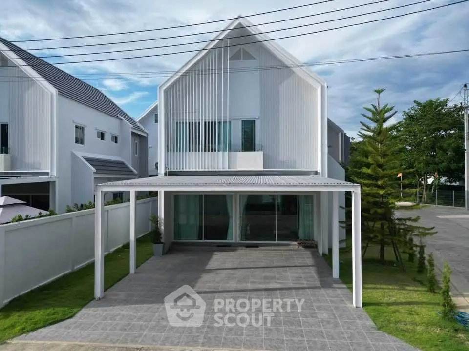 Modern white house with sleek design and spacious driveway in a serene neighborhood.