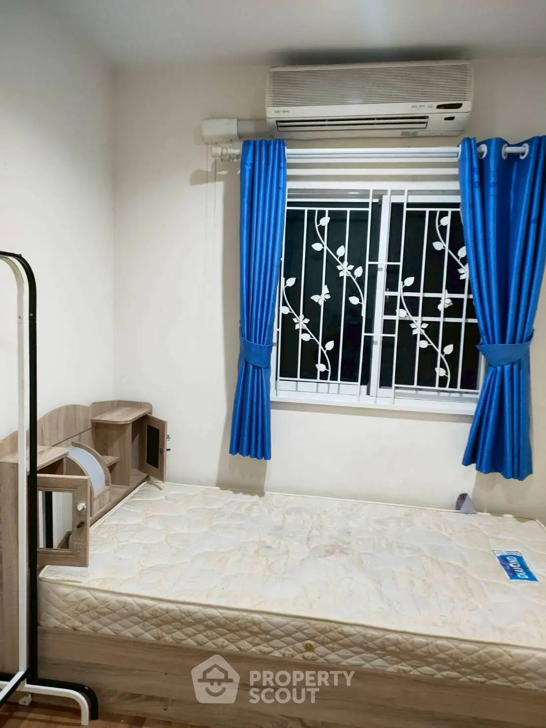 Cozy bedroom with air conditioning and stylish blue curtains, perfect for a comfortable living experience.