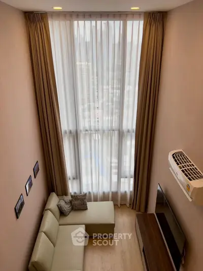 Modern living room with high ceiling and large window, featuring a cozy sofa and wall-mounted TV.