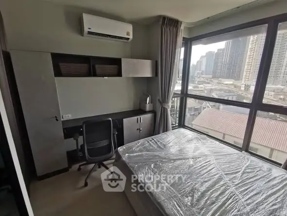 Modern bedroom with city view, featuring a desk and air conditioning, ideal for urban living.