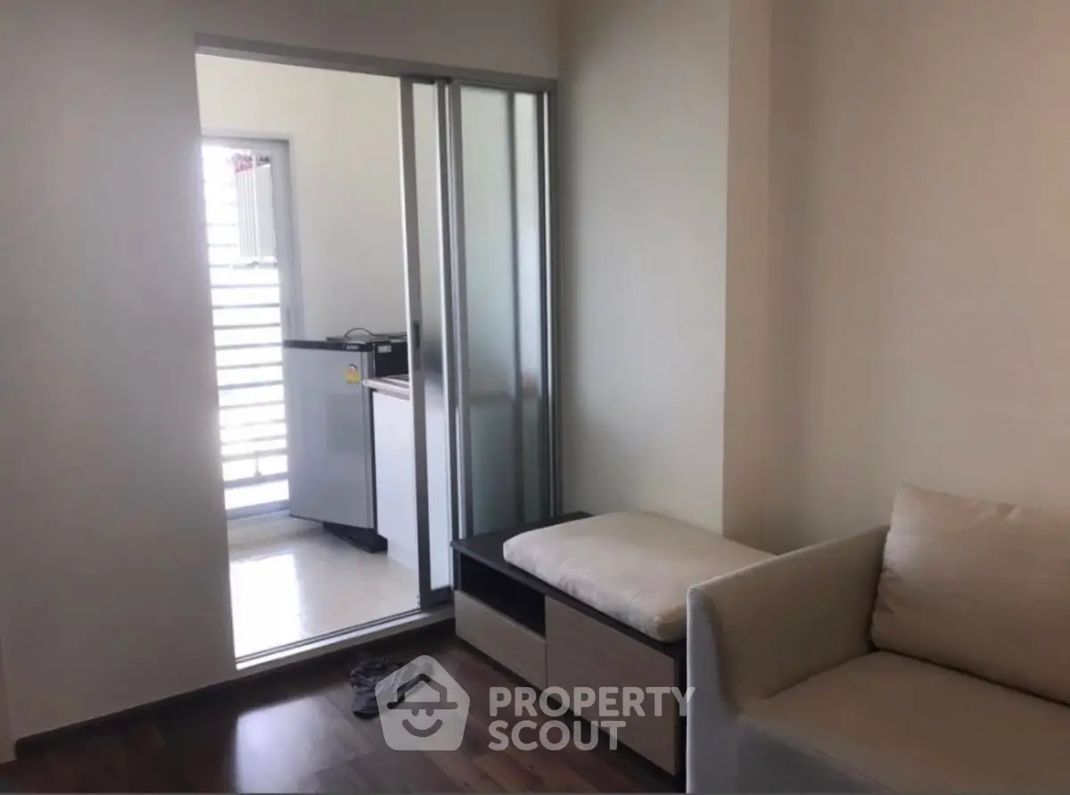 Cozy living area with sliding door leading to a bright kitchen space.