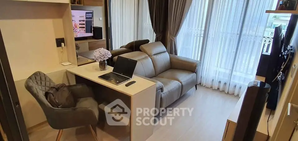 Modern living room with cozy sofa, work desk, and large windows with curtains.