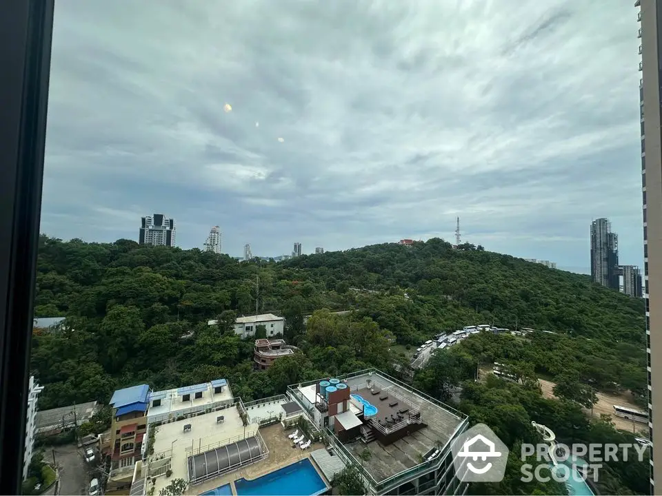 Stunning panoramic view from high-rise overlooking lush green hills and cityscape.