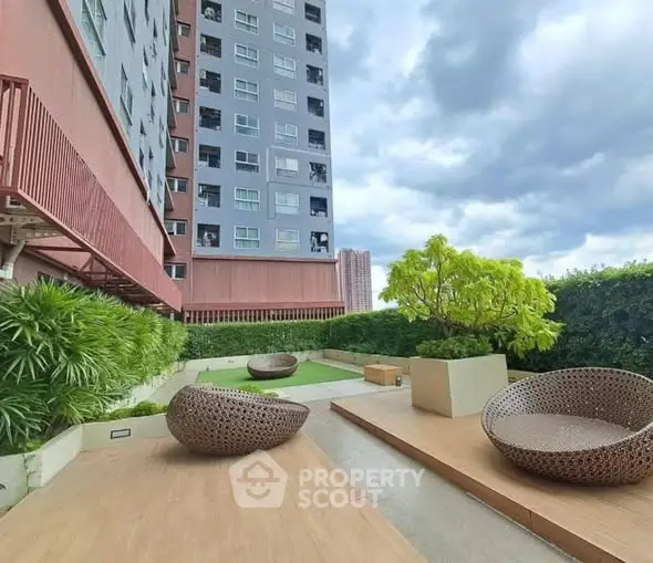 Modern apartment building with stylish outdoor seating area and lush greenery.
