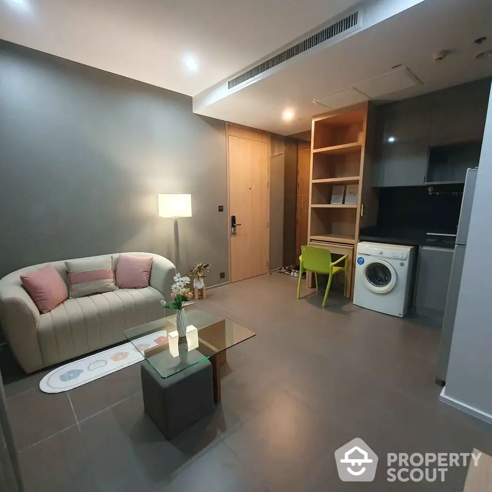 Modern living room with washing machine and stylish furniture in open layout apartment