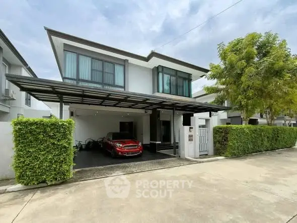 Modern two-story house with carport and lush greenery in a suburban neighborhood.