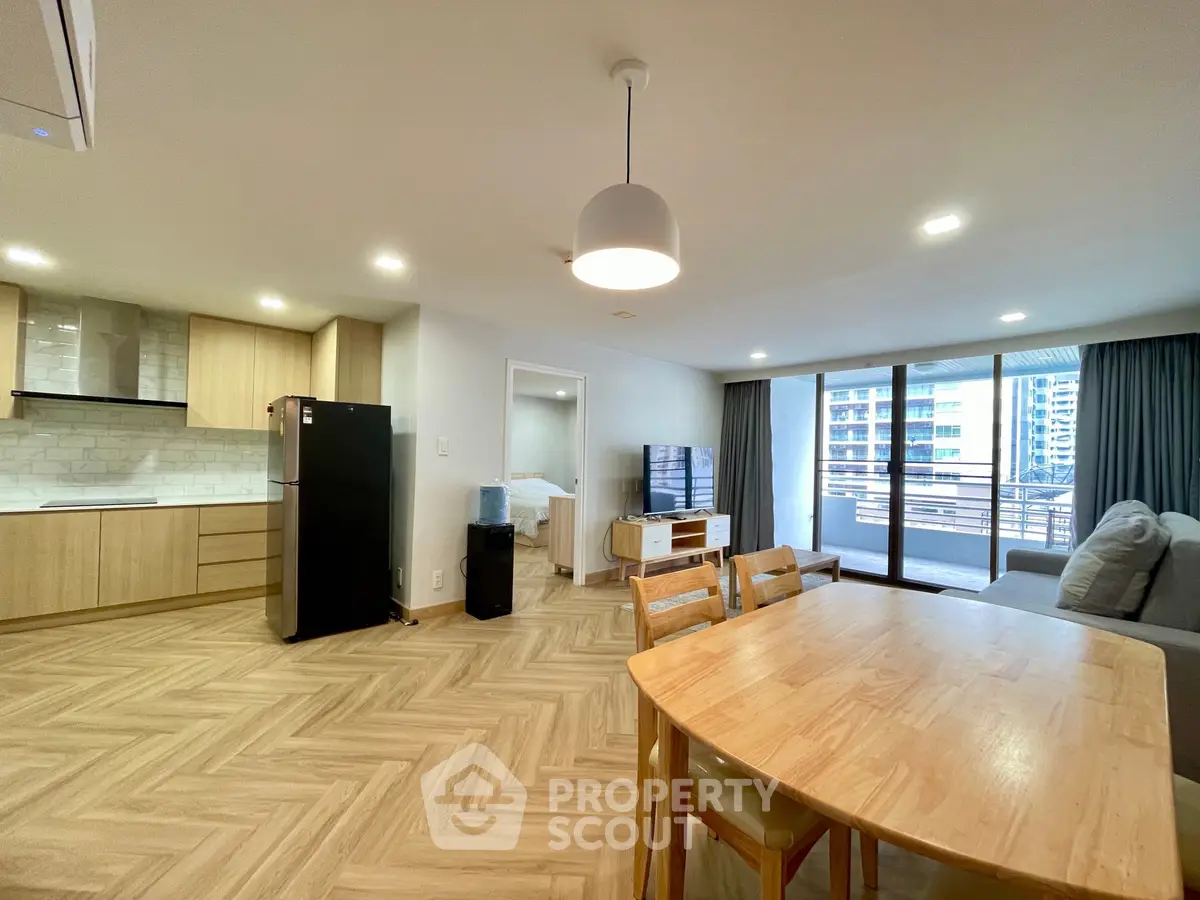 Spacious open-plan living room with modern kitchen and large balcony view.