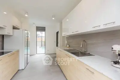 Modern kitchen with sleek cabinetry and pool view, featuring stainless steel appliances and ample natural light.