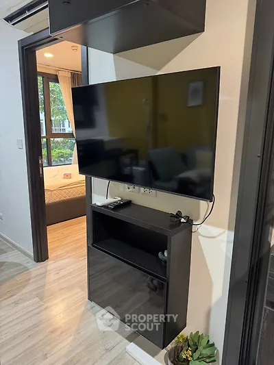 Modern apartment interior with wall-mounted TV and view into cozy bedroom