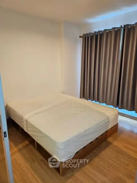 Cozy bedroom with wooden flooring and large window with curtains