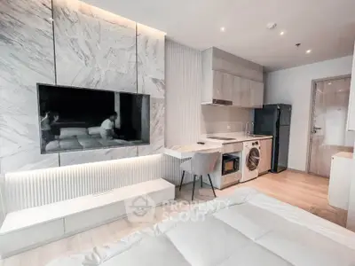 Modern studio apartment with sleek kitchen and cozy living area, featuring a built-in washing machine and stylish decor.