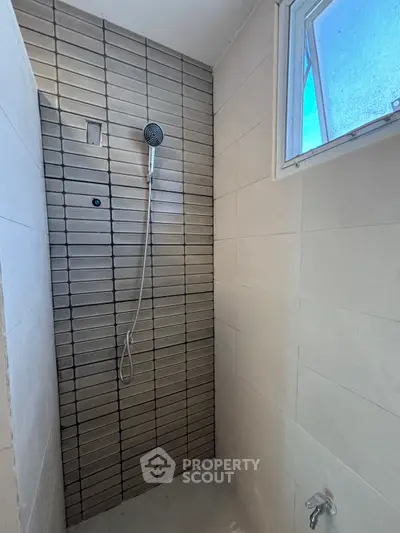Modern bathroom shower with sleek tile design and natural light window