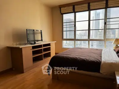Spacious bedroom with city view and modern furnishings in high-rise apartment.