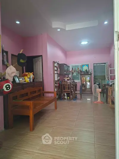Charming pink-themed living room with wooden furniture and dining area, perfect for cozy family gatherings.