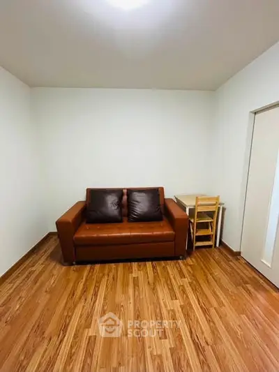 Cozy living room with brown leather sofa and wooden flooring, perfect for relaxation.
