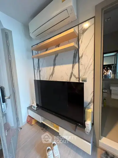 Modern living room with sleek TV setup and air conditioning unit, perfect for cozy entertainment.