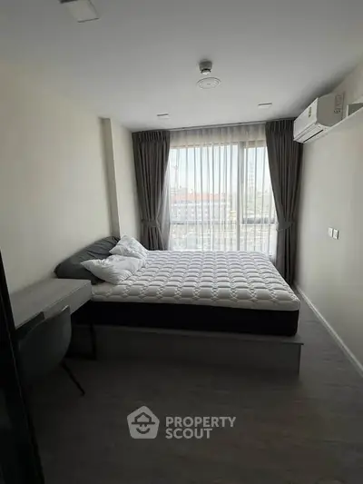 Modern bedroom with large window and natural light in a stylish apartment.