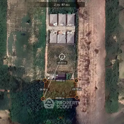 Aerial view of a property with plotted land measurements and adjacent buildings.