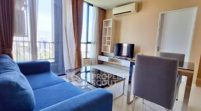 Modern living room with large windows, blue sofa, and sleek furniture in a high-rise apartment.