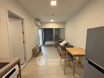Modern open-plan living room with dining area and bedroom in a cozy apartment.
