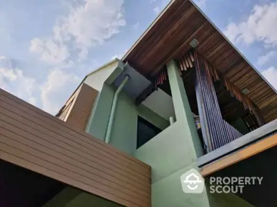 Modern architectural home exterior with unique wooden accents and sky view.