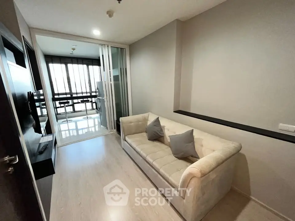 Modern living room with cozy sofa and glass partition leading to balcony