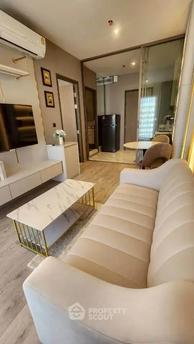 Modern living room with elegant beige sofa, marble coffee table, and wall-mounted TV in stylish apartment.