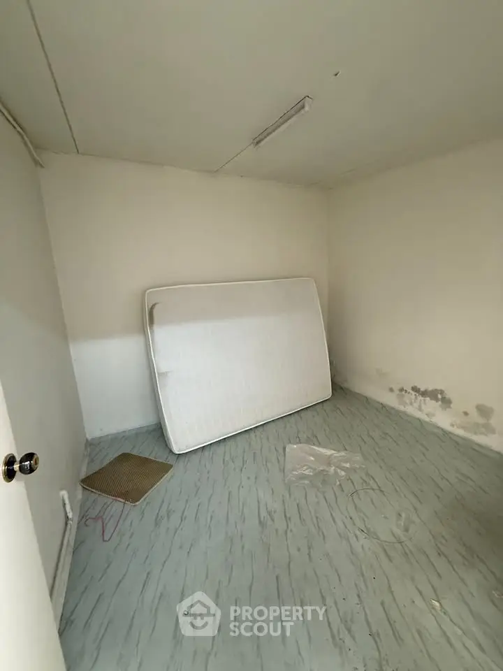 Minimalist room with mattress and simple flooring, ideal for renovation.