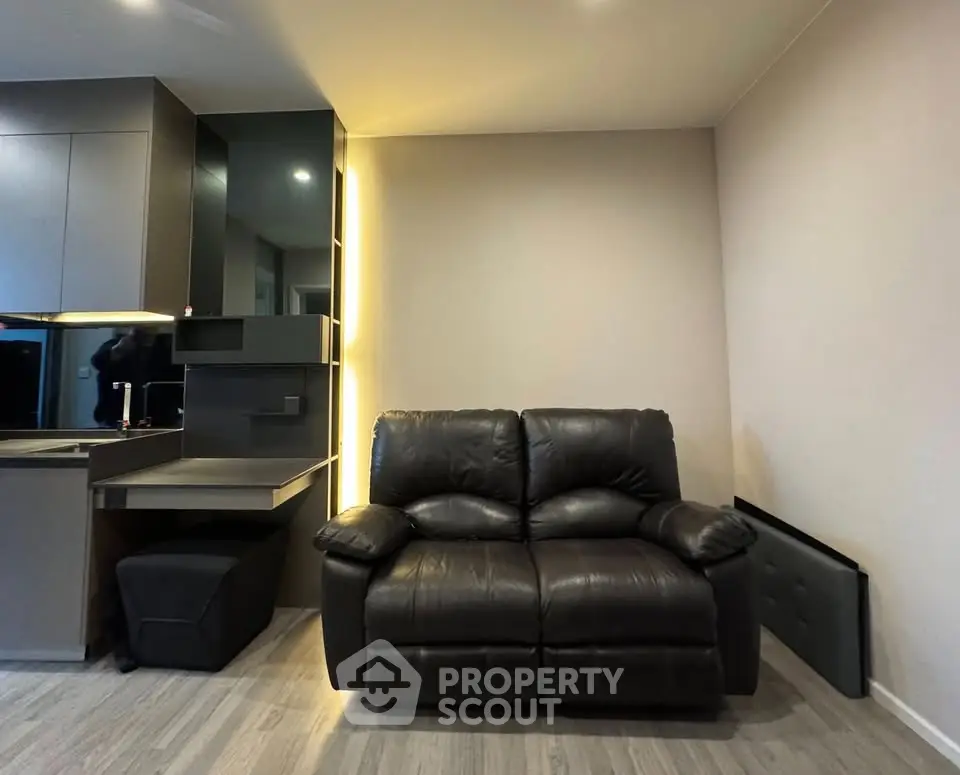 Modern living room with sleek leather sofa and stylish kitchen area