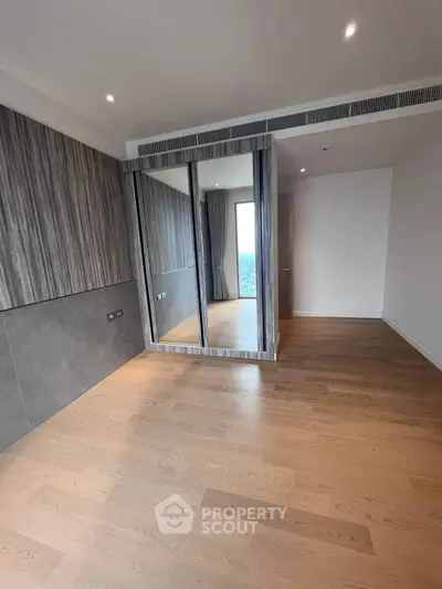Spacious modern bedroom with wooden flooring and mirrored closet doors