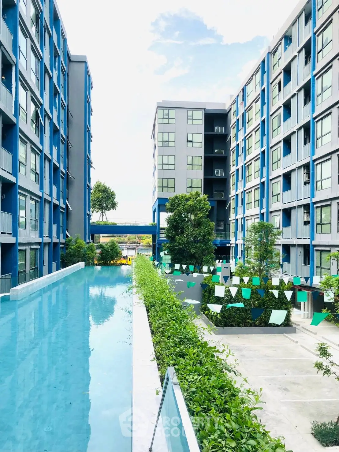 Modern apartment complex with pool and lush greenery, offering a serene urban living experience.