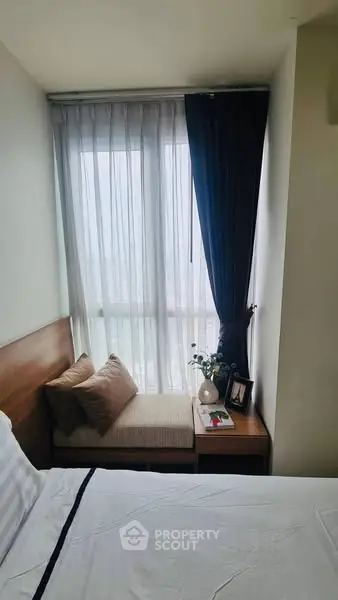 Cozy bedroom with large window and stylish decor in modern apartment.