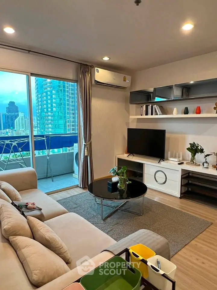 Modern living room with city view and balcony access in a high-rise apartment.