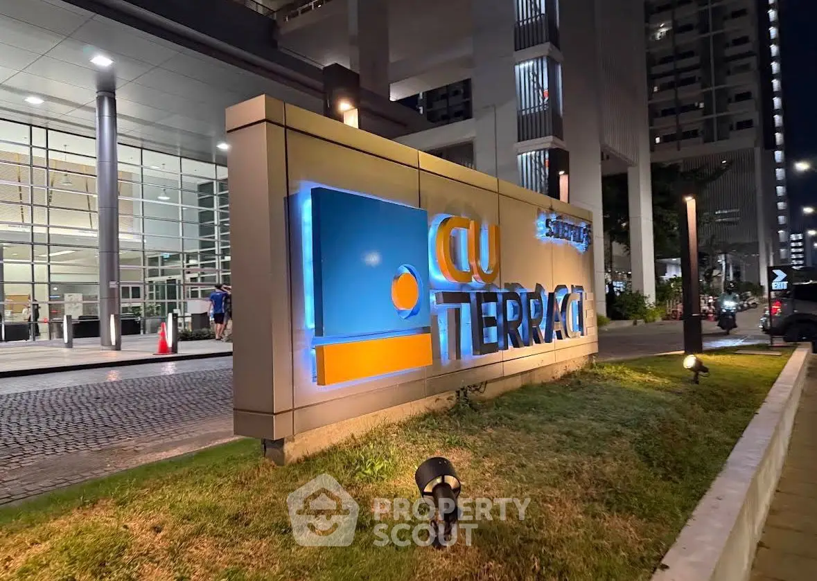 Modern building entrance with illuminated signage at night, showcasing sleek architectural design.
