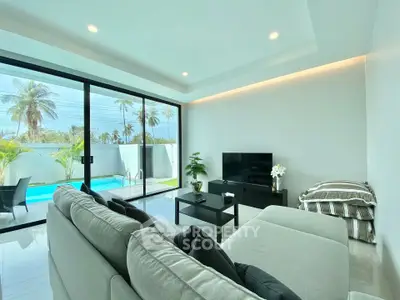 Modern living room with pool view, featuring sleek furniture and large glass doors for natural light.